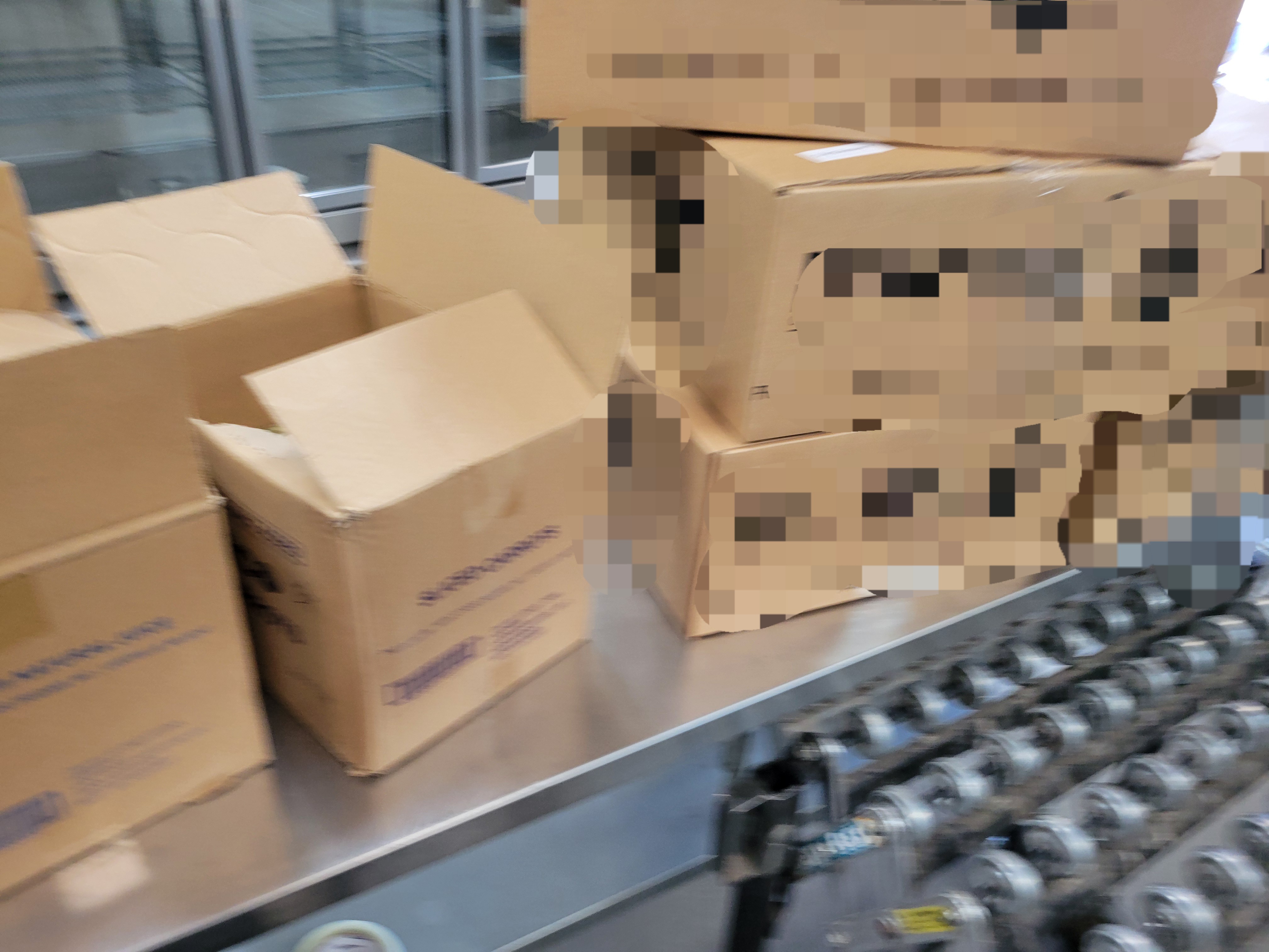 Cardboard boxes on metal table with closed conveyor belt in front of it.